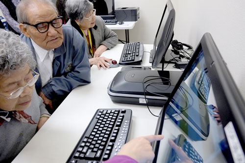 older computer users at a computer receiving help from an instructor