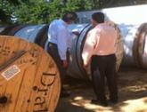 Two men standing with multiple spools of fiber-optic cable.