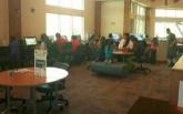 Computer Center Patrons sit at tables and use computers and tablets.
