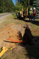 Workers discuss the positioning of a fiber-optic cable segment