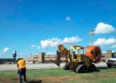 A construction worker feeds fiber into the ground to connect a local school to I