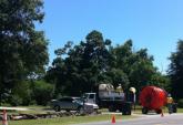 A construction crew stands with equipment and a spool of fiber.
