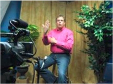 An interpreter signs on camera at a studio at the Deaf Action Center.