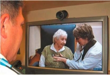 A doctor observes a nurse examining a patient via a broadband connection.