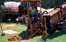 A member of Maryland DoIT drills a hole in the ground to deploy fiber.