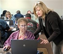 Instructor teaches woman how to use a laptop.